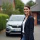 Femme souriante avec un SUV dans une allée résidentielle